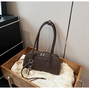 Detail of dark brown suede underarm bag with white stitching and silver double zippers