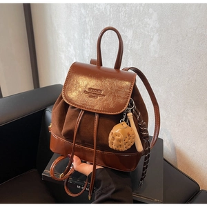 Detail of dark brown leather backpack with suede panel, drawstring closure and bag charm