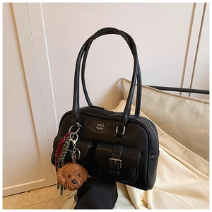 Detailed macro of black pebbled leather tote with dual buckle pockets and teddy bear charm