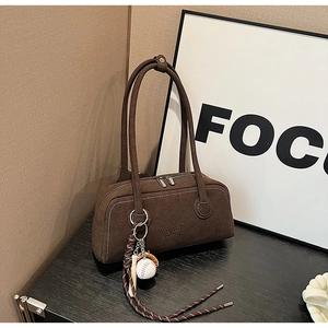Detail of brown suede tote bag with embossed letters and creative baseball charm