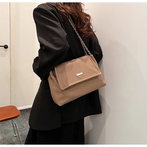 Détail d'un sac cabas plissé marron avec bandoulière chaîne porté par un modèle