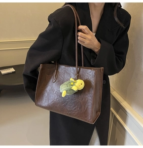 Brown crinkled leather tote bag with a cute green turtle plush pendant charm accessory