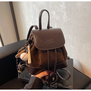 Detail of dark brown leather backpack with baseball charm and elegant drawstring closure