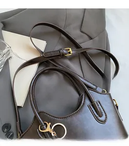 Dettaglio della borsa a secchiello in pelle marrone con tracolla e hardware dorato