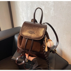 Detail of a dark brown mini backpack in suede and leather with baseball bat keychain