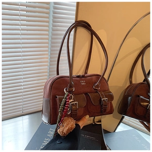 Detail view of vintage brown suede bowling bag with dual front pockets and bear charm
