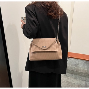Détail du sac cabas en velours côtelé kaki avec bandoulière chaîne porté par un mannequin