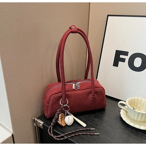 Detail view of burgundy frosted leather handbag with premium baseball charm accessory