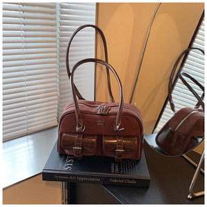 Detail of vintage brown suede bowling bag with buckle pockets on an art book