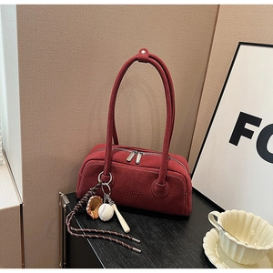 Detail of red suede Boston bag featuring double metal zippers and creative keychains