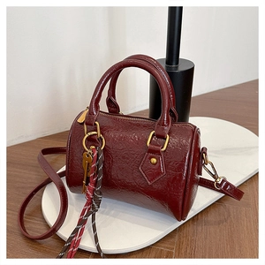 Detail of burgundy boston bag with crushed texture leather and golden key ornament