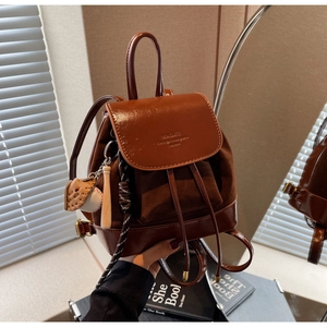 Close-up of brown mini backpack with leather texture and baseball bat charm detail