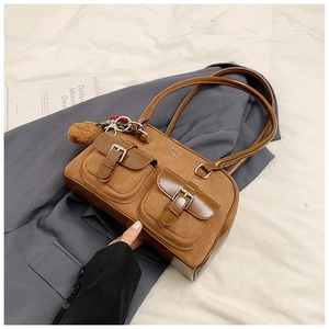 Detail of caramel brown bowling bag with suede texture and front buckle pockets