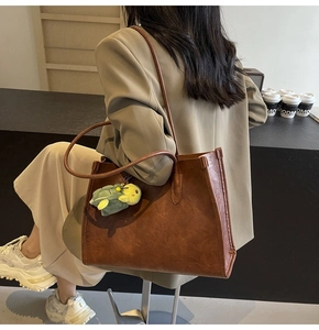 Brown faux leather tote bag with vintage texture and green turtle plush charm decoration