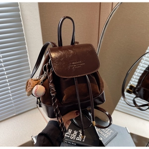 Detail of dark brown leather backpack with baseball charm and matte patchwork finish