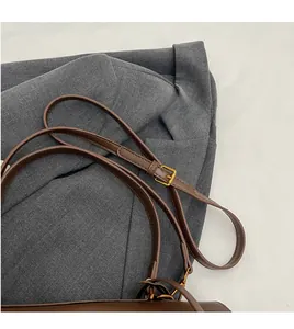 Detail of adjustable long brown leather strap with polished golden metal buckle