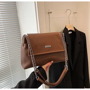 Détail de la texture en velours côtelé marron et de la chaîne argentée du sac vintage