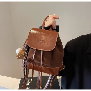 Detail of vintage brown dual-texture backpack with magnetic flap and baseball charm