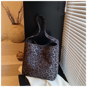 Chic leopard print bucket bag in grey tones placed on a minimal white table with shadows