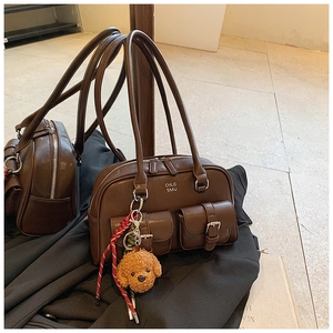 Detail of vintage brown leather bowling bag with front pockets and teddy bear charm