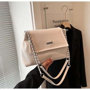 Détail du sac cabas en velours côtelé blanc cassé avec chaîne argentée et logo métal