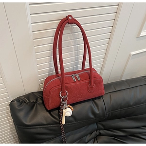 Detail of red suede underarm bag with silver zipper and baseball charm accessory