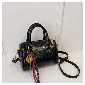 Detail showing shiny black pleated leather texture and heart padlock charm of Boston bag