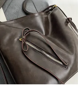 Detail of dark brown tote bag with smooth faux leather texture and decorative bow
