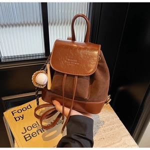 Detail view of brown bucket backpack with drawstring closure and baseball charm