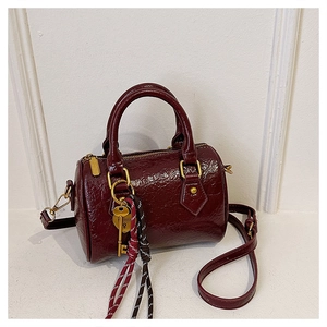 Detailed macro of burgundy Boston bag with glossy wrinkled leather and golden hardware