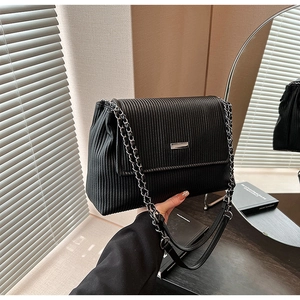 Gros plan sur le sac cabas plissé noir avec chaîne argentée et détail métallique