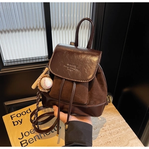 Retro brown PU leather and suede backpack with baseball charm detail shown in hand
