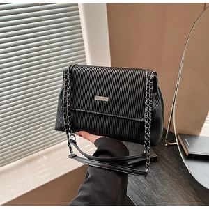 Détail du sac à bandoulière plissé noir avec chaîne argentée et plaque logo métal