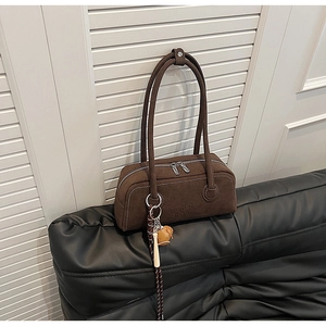 Close-up of brown suede bowling bag texture with MUHETI embossed logo and metal zipper