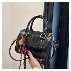 Detail of black pleated Boston bag featuring golden hardware and heart key pendant