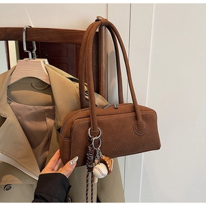 Brown frosted leather shoulder bag detailing with baseball charm on a wooden hanger