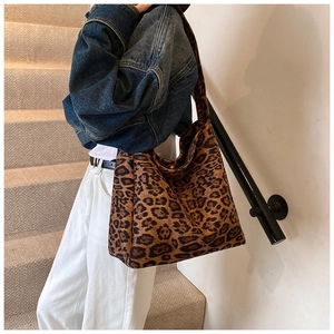 Fashionable leopard print tote bag styled with denim jacket and white pants on stairs