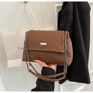 Détail d'un sac bandoulière plissé marron avec boucle argentée et chaîne métallique