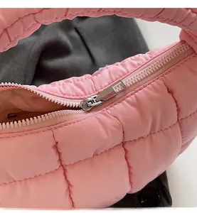 Detailed close-up of smooth silver metal zipper on pink quilted puffer handbag