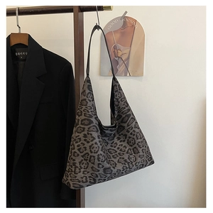 Detail of leopard print tote bag in dark grey canvas hanging on a wooden hanger
