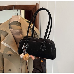 Detail of black suede underarm bag with sports charms and embossed logo texture