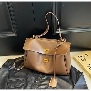 Detail of vintage brown tote bag featuring dual gold turn-lock closures and matte leather texture