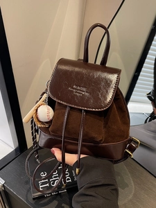 Fashionable dark brown dual-material backpack with drawstring flap and baseball charm