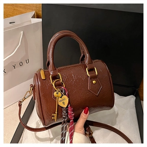 Detail of glossy brown Boston bag with golden heart lock and luxury wax leather texture