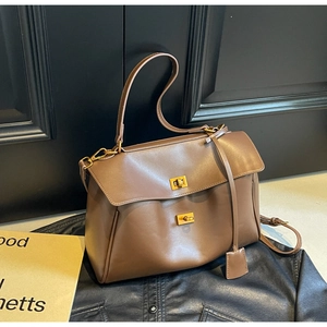 Close-up of brown leather tote bag with elegant golden turn-lock and vintage strap detail