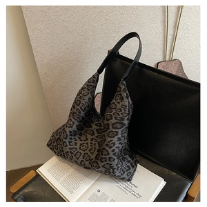 Detail view of leopard print tote bag placed on leather chair with aesthetic book
