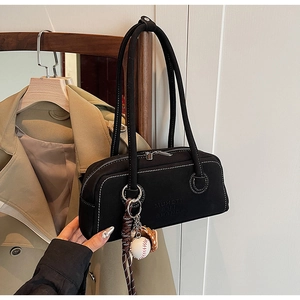 Detail of black underarm bag with white contrast stitching and baseball charm on a hanger