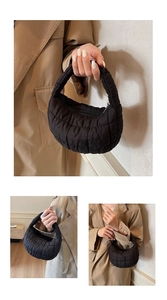Detail of black quilted puffer crescent bag showing soft texture and padded nylon handle