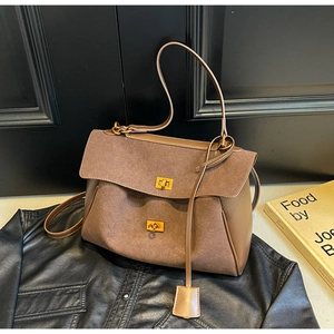 Detail of a brown tote bag with gold twist lock and smooth suede leather patchwork