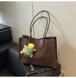 Detailed texture of dark brown wrinkled leather tote bag with a cute turtle charm